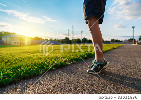 teen boy boy does physical exercises at the stadium track, close view of the legs, a soccer field with green grass - concept of sports and health teen boy boy does physical exercises at the stadium track, close view of the legs, a soccer field with green grass - concept of sports and health 83031836
