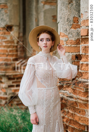 Pretty young caucasian redhead girl in a garden and outside with her wedding bouquet. Beautiful redhead bride. 83032500