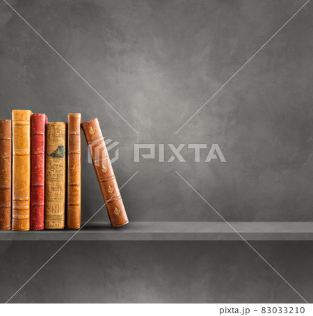 Row of old books on grey shelf. Square background 83033210
