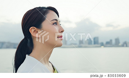 都市の前で遠くを見つめる女性 83033609