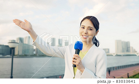 都市の前に立つ女性アナウンサー 83033641