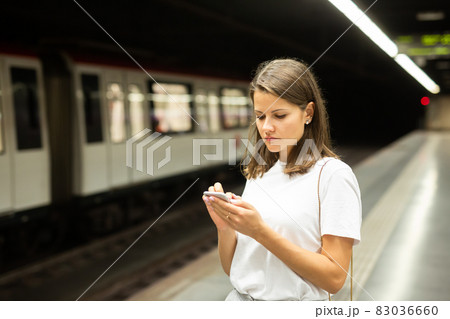 Woman waiting subway car using phone Woman waiting subway car using phone 83036660