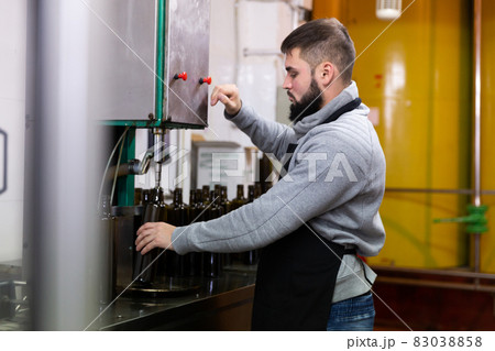 Young man working on olive oil bottling line 83038858