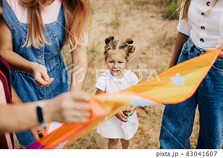 Close-up of a little girl watching her mother prepare a kite for launch 83041607