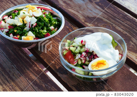 Fresh vegetables salad with eggs in bowls on wooden table. 83043020