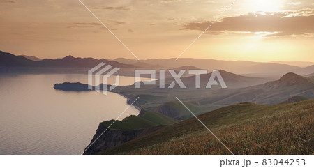 Beautiful sunset with rays over the contours of mountains with stones and sea. 83044253