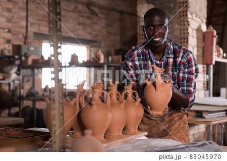 Potter checking quality of ceramic objects 83045970