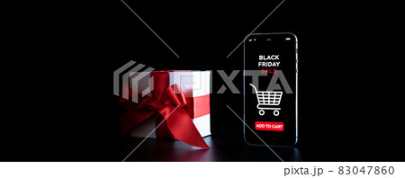 Online shopping gifts. Black Friday banner with internet shopping app on mobile phone, white gifts with red bow falling on black background. Present online concept. Online shopping gifts. Black Friday banner with internet shopping app on mobile phone, white gifts with red bow falling on black background. Present online concept. 83047860