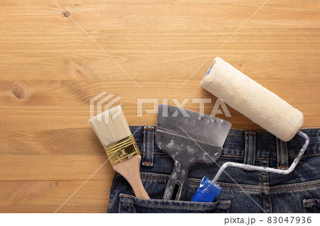 Kit of paint tool in jeans pocket at wooden table background. House renovation concept Kit of paint tool in jeans pocket at wooden table background. House renovation concept 83047936