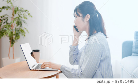ノートパソコンを使いながら電話をする女性	 83051499