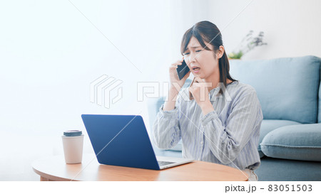 ノートパソコンを使いながら電話をする女性	 83051503