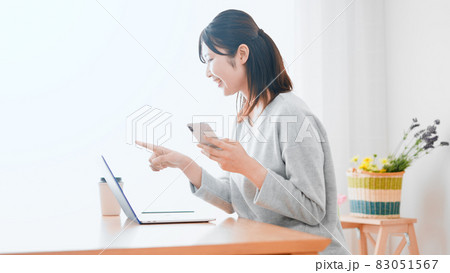 ノートパソコンとスマートフォンを使う女性 83051567