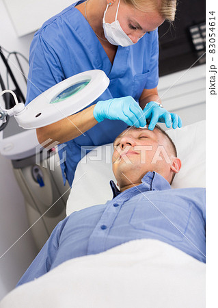 Female doctor is doing cleaning skin procedure to client Female doctor is doing cleaning skin procedure to client 83054614