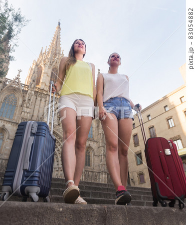 Cheerful female tourists are walking throught the old european city Cheerful female tourists are walking throught the old european city 83054882