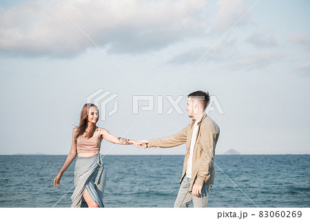 Beautiful young couple on the beach. Holding hands and looking to each other. Honeymoon.High quality photo 83060269