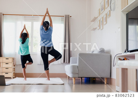 Asian young mother and her daughter doing stretching fitness exercise yoga together at home. Parent teaching child work out to be strong and maintain physical health and wellbeing in daily routine. 83062523