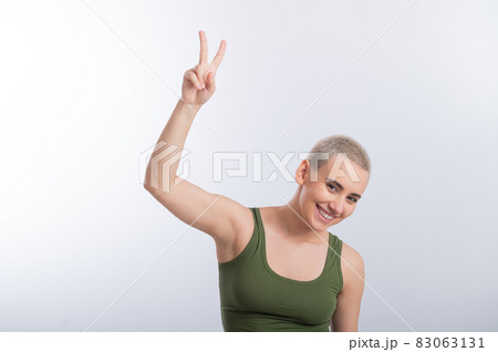 Young Caucasian Woman Holding Raised Hand White Background Smiling Girl Green Tshirt Short Blond Hair. 83063131
