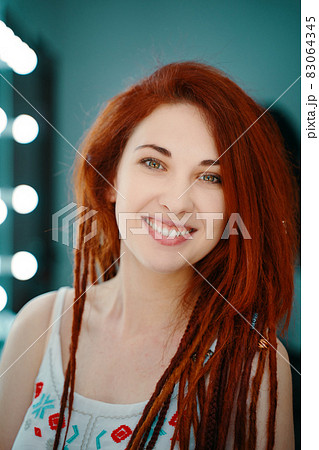 Smiling red-haired girl with long dreadlocks. 83064345