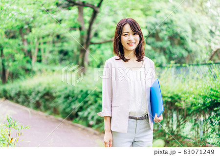 書類を持って歩く若いビジネスウーマン 83071249