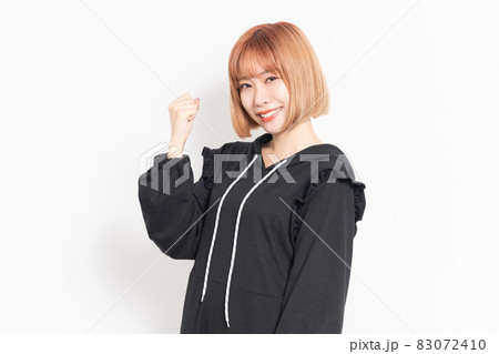 ガッツポーズをするカジュアルな服装の女性 83072410