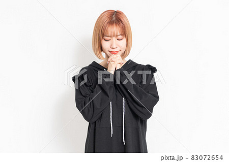 お願いのジェスチャーをするカジュアルな服装の若い女性 83072654
