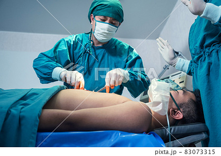 Asian surgeon in surgical gown operating with accident patient at hospital Asian surgeon in surgical gown operating with accident patient at hospital 83073315