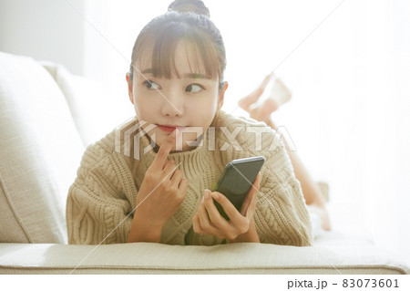 ソファでスマホを操作する若い女性 ソファでスマホを操作する若い女性 83073601