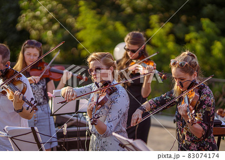 Musical ensemble playing violin at outdoor concert 83074174