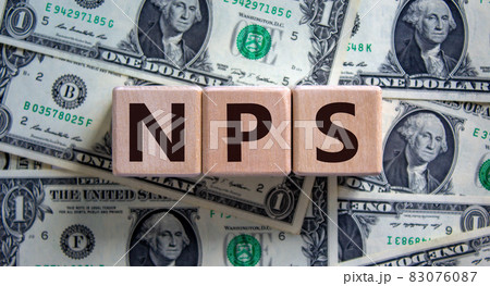 Wood cubes with acronym 'NPS' - 'net promoter score' on a beautiful background from dollar bills. Business concept, copy space. 83076087