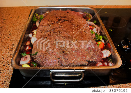 A moose brisket on a bed of vegetables in a roasting pan 83076192
