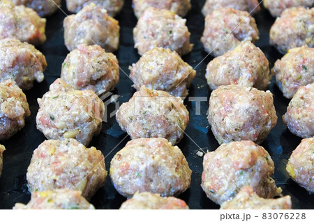 Raw turkey meatballs on a black cooking sheet 83076228