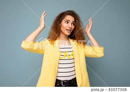 Photo shot of young emotional attractive brunette curly woman with sincere emotions wearing trendy Photo shot of young emotional attractive brunette curly woman with sincere emotions wearing trendy 83077308