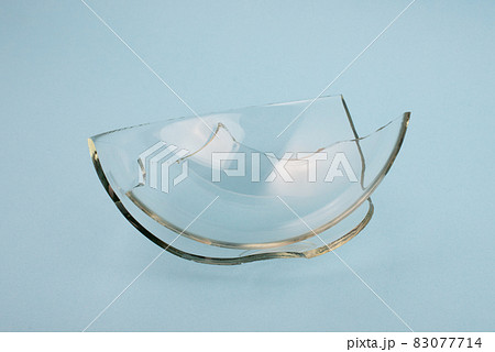 Broken glass pieces on pastel blue background. Broken glass pieces on pastel blue background. 83077714