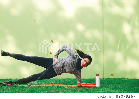 Young woman do side plank on the mat outdoors Young woman do side plank on the mat outdoors 83079267