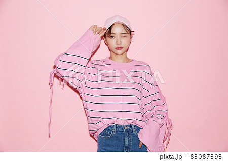 スポーティーなファッションをした若い女性のピンク背景のポートレート 83087393