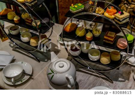 Traditional English afternoon tea desserts with beautiful snacks , Clotted cream and jam, strawberries, with various sandwiches on the background, selective focus. 83088615