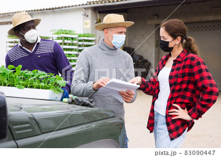 Female gardener in protective mask discussing contract with representative of company Female gardener in protective mask discussing contract with representative of company 83090447