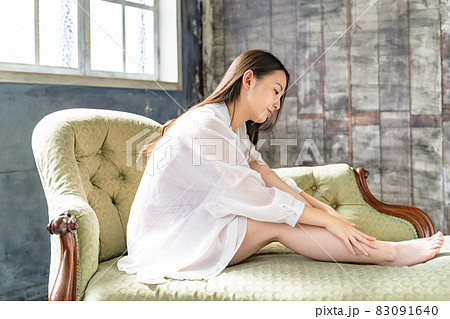 自分の足をケアする若い女性　ロングヘア 83091640