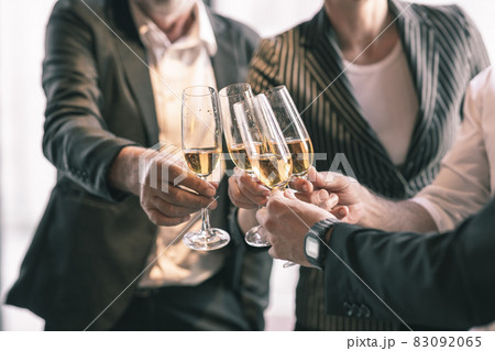 Business team celebrating their success together by making a toss with a champagne glass. They are wearing suit and white shirt. 83092065