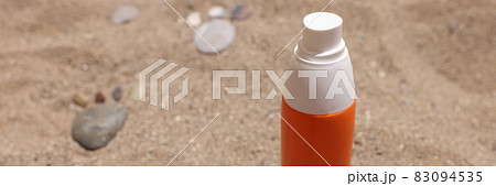 Bottle of sunscreen lotion sits on hot sand Bottle of sunscreen lotion sits on hot sand 83094535