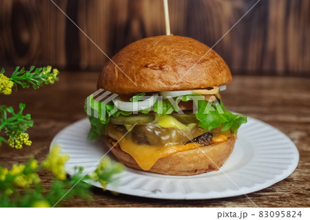 Close-up of a standard burger. Adult fast food in a restaurant or cafe. Macro photo of burger ingredients with meat, cheese and herbs. Eco burgers for the whole family Close-up of a standard burger. Adult fast food in a restaurant or cafe. Macro photo of burger ingredients with meat, cheese and herbs. Eco burgers for the whole family 83095824