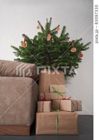 presents in paper wrap with ribbons under christmas tree indoor near couch with warm light 83097330