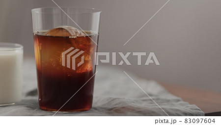 pour cold brew coffee in tumbler glass on walnut table 83097604