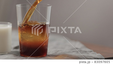 pour cold brew coffee in tumbler glass on walnut table pour cold brew coffee in tumbler glass on walnut table 83097605