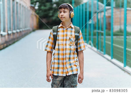 happy teen boy portrait on the way to school, he is listening to music on headphones, education and back to school concept 83098305