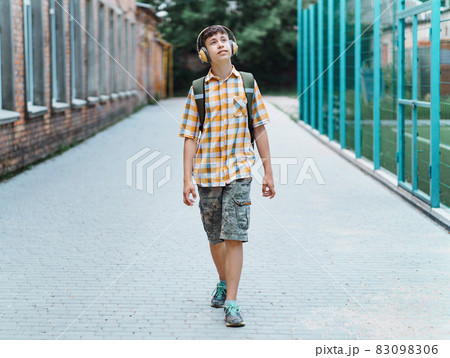 happy teen boy portrait on the way to school, he is listening to music on headphones, education and back to school concept happy teen boy portrait on the way to school, he is listening to music on headphones, education and back to school concept 83098306