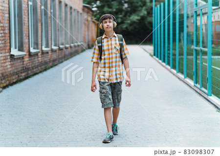happy teen boy portrait on the way to school, he is listening to music on headphones, education and back to school concept happy teen boy portrait on the way to school, he is listening to music on headphones, education and back to school concept 83098307