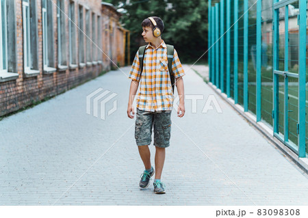 happy teen boy portrait on the way to school, he is listening to music on headphones, education and back to school concept happy teen boy portrait on the way to school, he is listening to music on headphones, education and back to school concept 83098308
