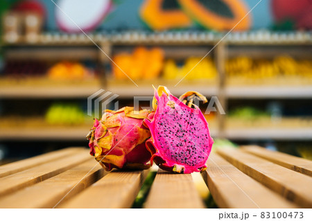 Close-up front view of fresh juicy pitahaya standing on wooden pallet at fruit and vegetables section of grocery store. Close-up front view of fresh juicy pitahaya standing on wooden pallet at fruit and vegetables section of grocery store. 83100473