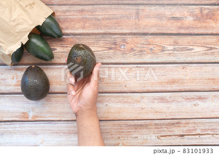 top view of hand hold a slice of avocado on wooden table  83101933